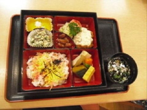 区切られた赤いトレーに、ちらし寿司や赤豆などが盛り付けられている食事