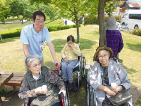 緑豊かな木々の下で、スタッフと共にくつろいでいる入居者たち