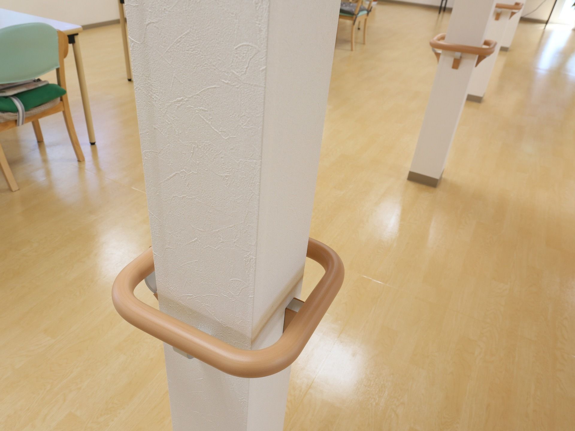 フローリングの床の部屋に数本の白い柱が立っている。ぐるっと囲うようにそれぞれの柱に手すりが設置されている。