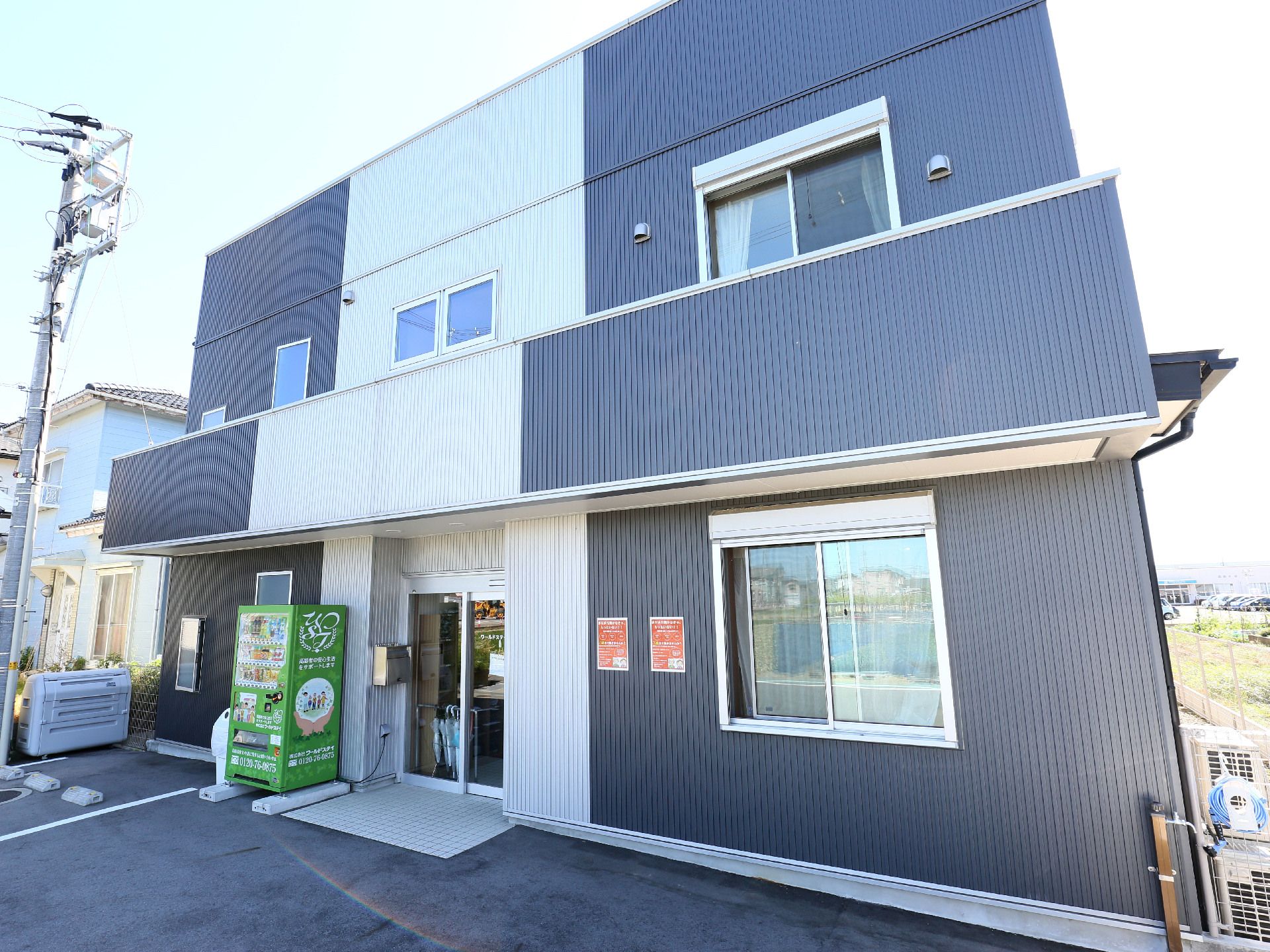 玄関脇に自動販売機が設置されている、二階建ての施設外観