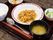 黒いお盆には箸とスプーン、ご飯、お味噌汁、その他3品の食事が乗っている。メインにはニンジンやピーマンなど野菜が多く使われている。