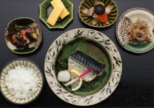 白飯に主菜の魚料理をはじめ、卵焼きや煮物などの副菜が数種類並んだ、栄養バランスの良い和食のメニューである。