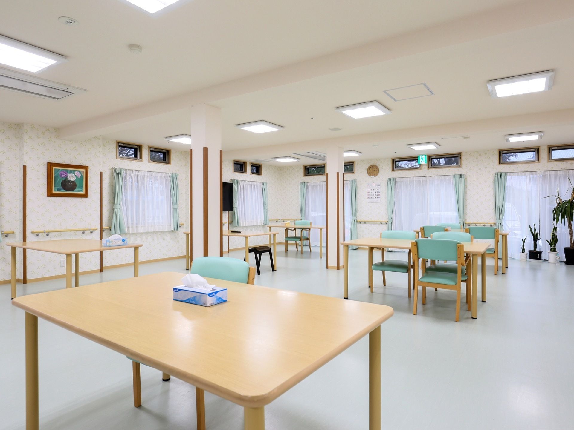 一番右に設置された窓の手前に観葉植物が複数置かれている。窓の左側の壁には絵画が1枚額縁に入って飾られている。