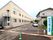 施設名が書かれた縦型の看板が建てられている。建物の右側に駐車スペースが用意されている。道路側に向かって外階段が設置されている。