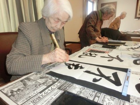 入居者様たちが新聞紙を敷き、習字道具を用意して真剣に習字に取り組んでいる。字はとても達筆で綺麗である。