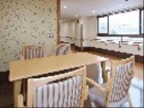 ４人用の木製のテーブルと、手すり付きの椅子が置かれている。近くには広い窓があり、明るい雰囲気である。