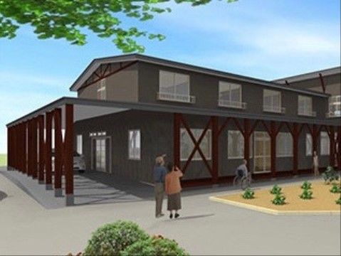 シックな色合いの外壁のモダンな建物である。広々とした玄関前のエントランスには屋根があり、バリアフリーとなっている。