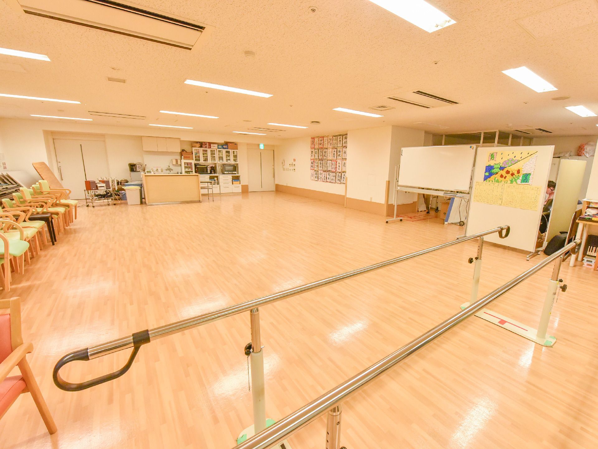 居住者の方がいろいろな活動を楽しめるフローリングの広々とした共有スペース。リハビリ用の歩行訓練器も完備。