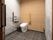 広々としたモダンスタイルのトイレである。天井が高いので開放感がある。手すりやナースコールが完備されている。