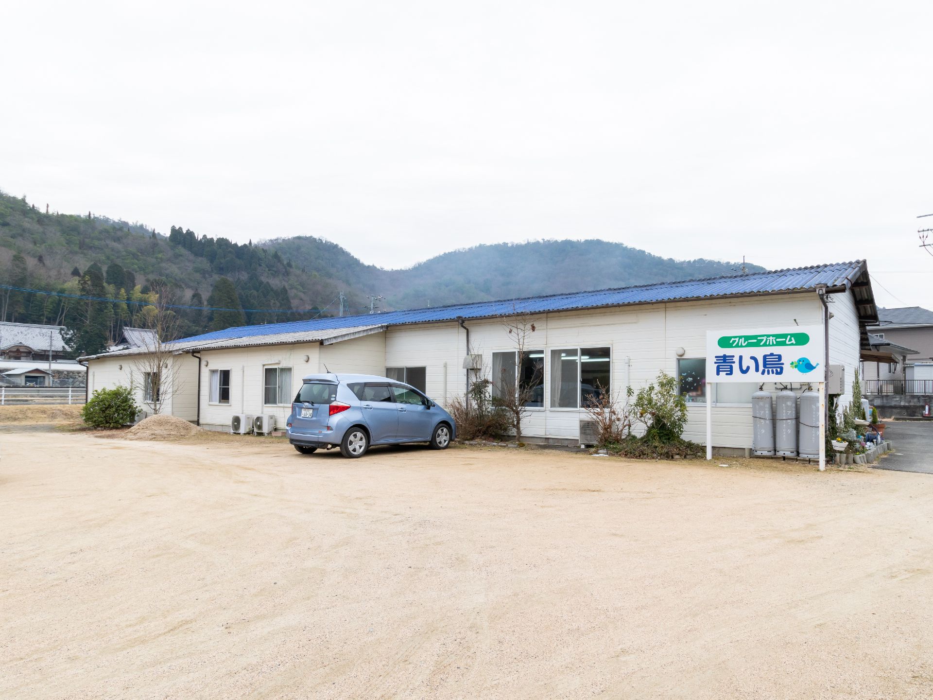 山の自然のすぐそばに位置する広々とした敷地に建てられた平屋建ての施設建物