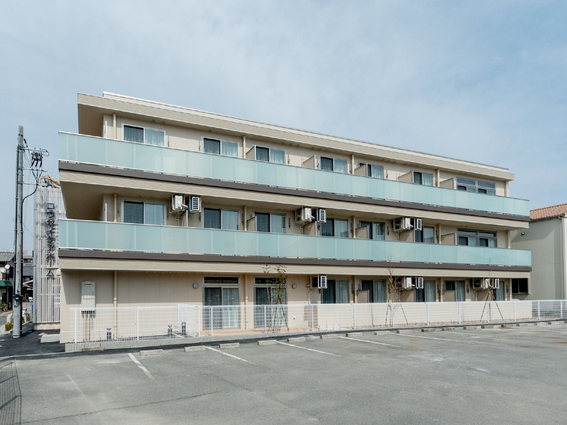 3階建てのすっきりとした外観の建物。ベランダが広くとられていて、採光も十分ある。また駐車スペースも広く安心である。