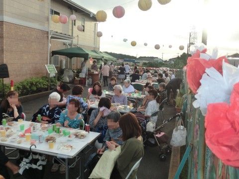 施設屋外でのお祭りのイベントで、食事を楽しむ入居者様と家族