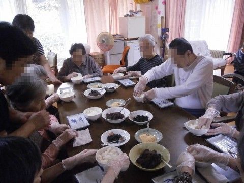 食卓に集まって、おにぎりを自分で作るイベントに参加する入居者様