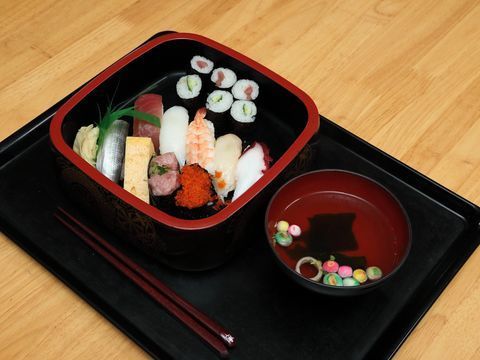 お寿司や手巻き寿司の盛り合わせである。いくらやマグロ、鉄火巻き等の多種類のお寿司が並べられている。お吸い物もつけられている。