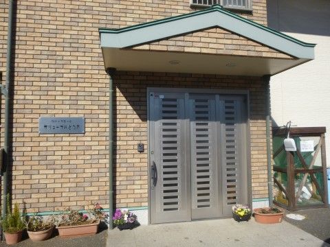 自宅の玄関のような雰囲気の、スライド式ドアを備えた日当たりの良いエントランス
