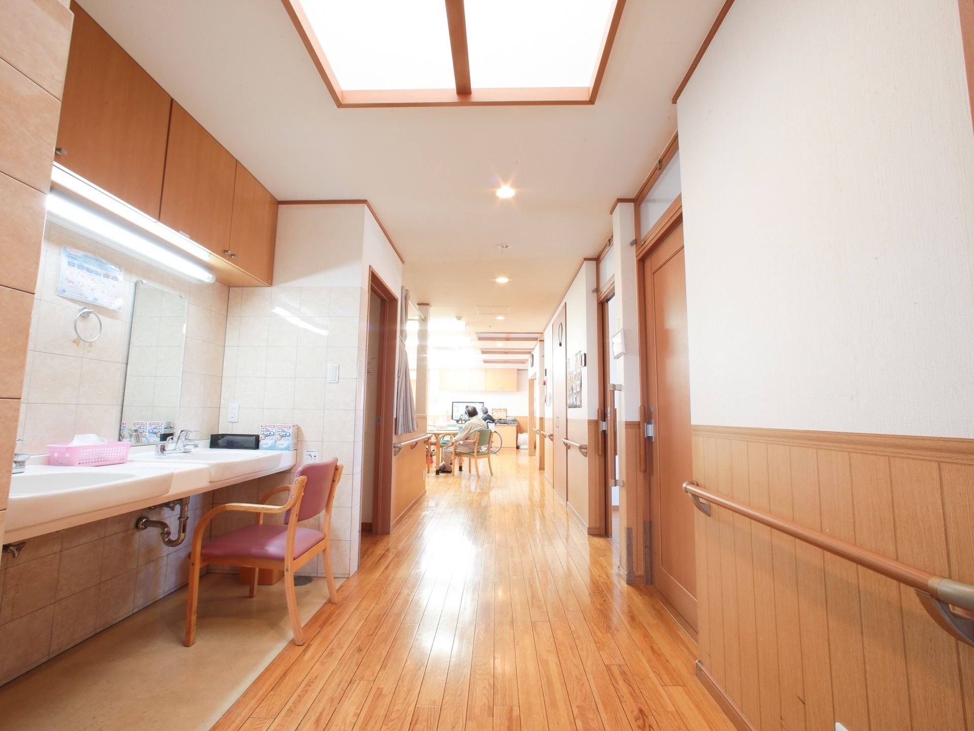 通路に沿って手すりを設置している。通路に２つの洗面台を設置している。１つには椅子を用意している。シンクは浅く、足の邪魔にならない。
