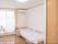 フローリングの広い部屋に、電動ベッドが設置されている。サイドテーブルとエアコンがついている。手前にはクローゼットがある。