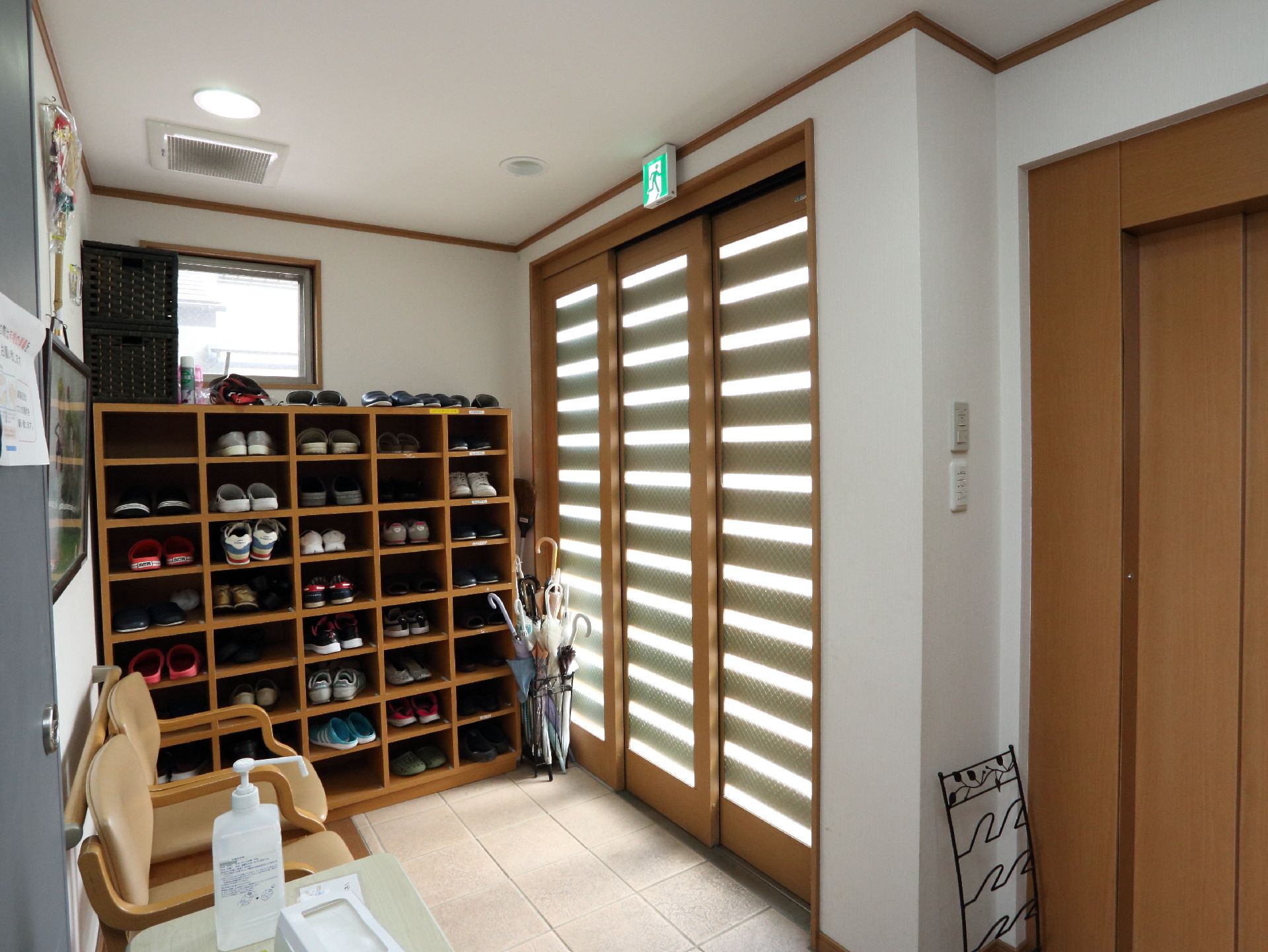 木製の靴箱が玄関に置いてある。椅子が二脚置いてあるので、腰かけて靴を履き替えたりできる。傘立てがある。