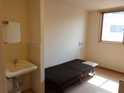 洗面台、鏡、ベッドが備えられた、日当たりのよい居室