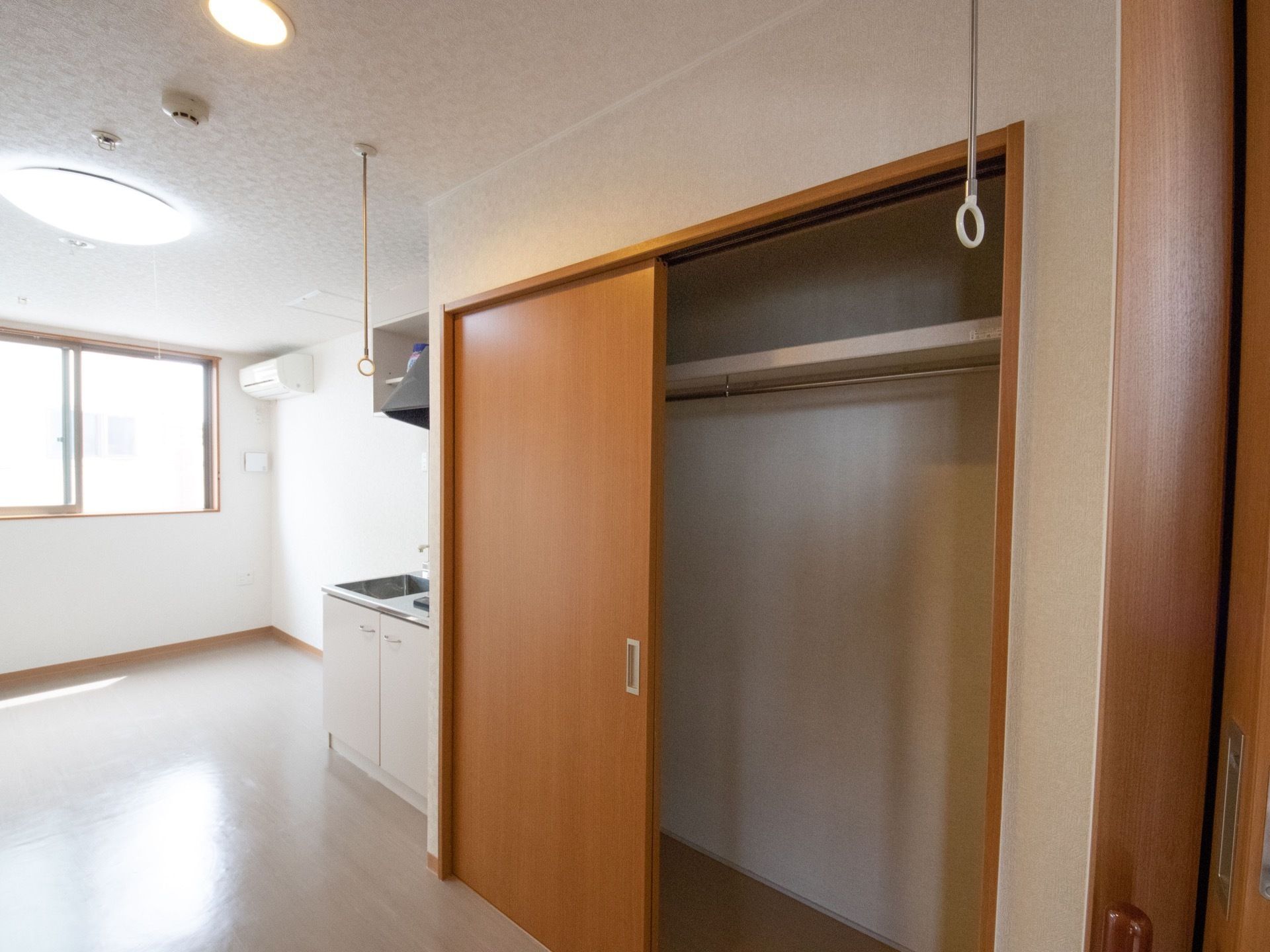 居室には、広々とした収納庫を備えている。内部は上に棚があり、その下にポールを取付けている。横側にキッチンを設置している。