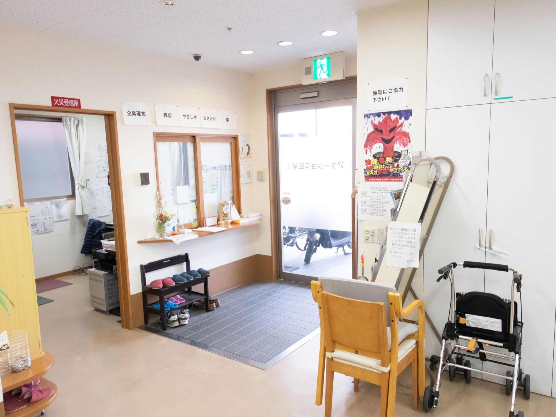 ガラス張りの玄関ドアから右側に受付窓口がある。カウンターの上に時計、筆記用具などを置き、端に花を飾っている。