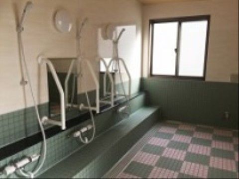 複数のシャワースペースが用意され、壁に手すりがついている浴室