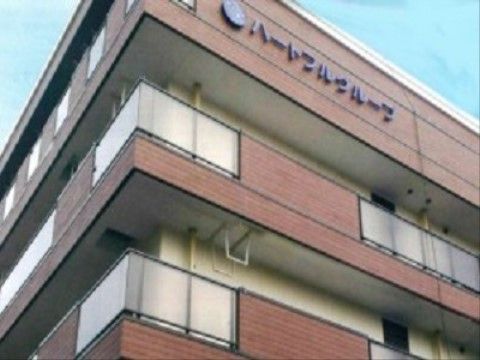 各階の外側にベランダが設けられ、最上階の屋根部分に施設名が書かれている外観