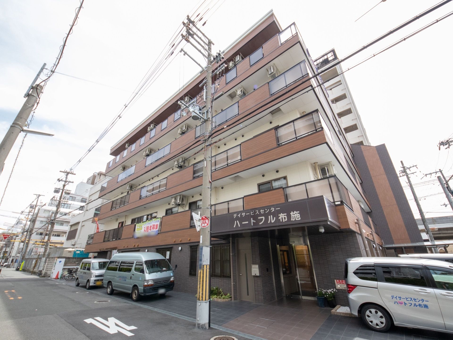 施設は5階建てで、茶色と白で統一された外観となっている。建物の右側には、施設の玄関が設けられている。
