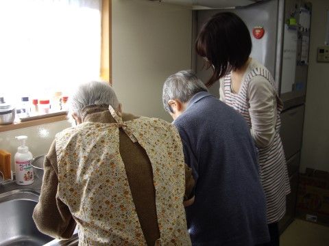 スタッフのサポートを受けて、キッチンで料理をする入居者様