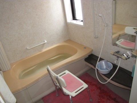 浴室には窓があり、明るい。１人用の浴槽が設置されている。壁面には手すりが付いている。鏡付きのシャワー台、シャワーチェアーが設置されている。