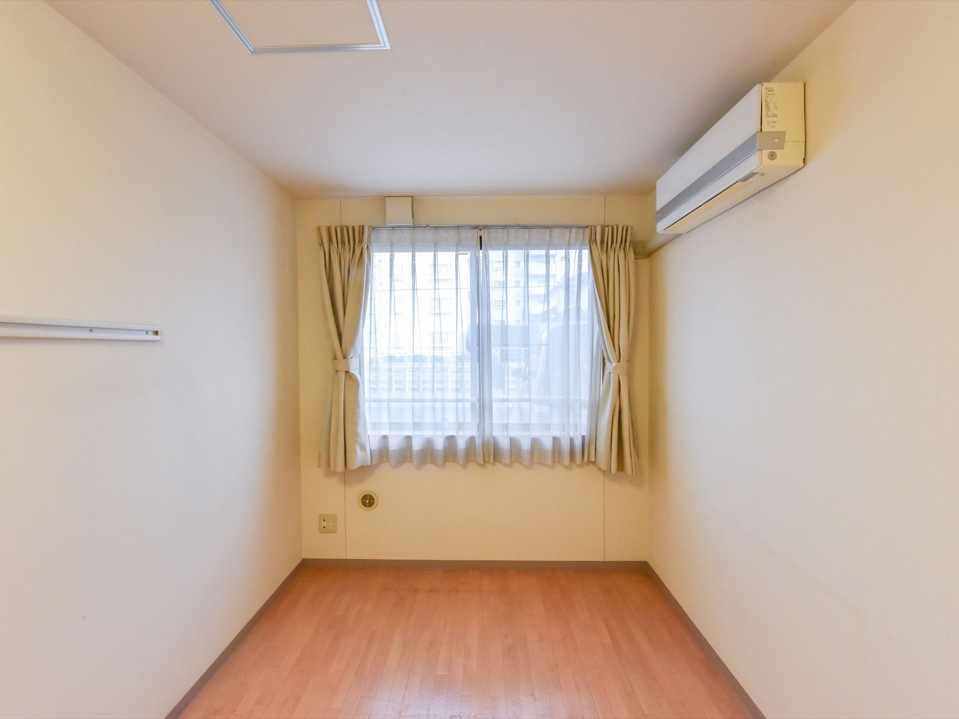 居室の壁には大きめの腰高窓を設け、日差しを調整するダブルカーテンをかけている。エアコンを一台設置している。