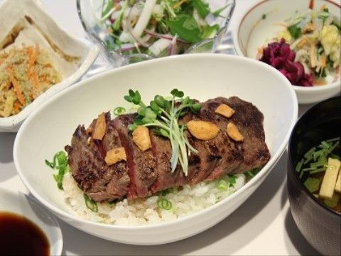 ステーキ丼を中心に、サラダや副菜が用意されているバラエティーに富んだ食事の一例