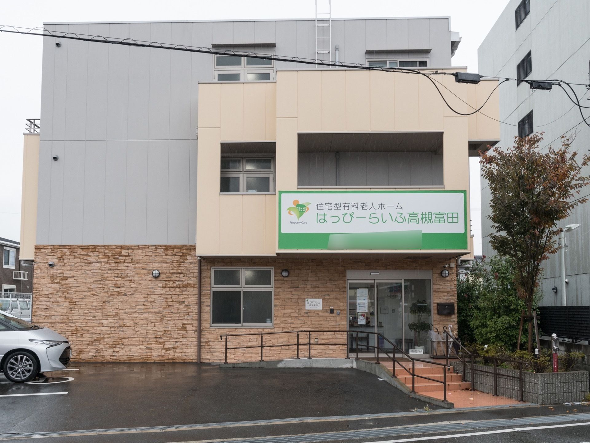 施設は３階建てで１階に入口がある。入口までは数段の階段やなだらかなスロープを利用できる。入口上部に施設の看板がある。