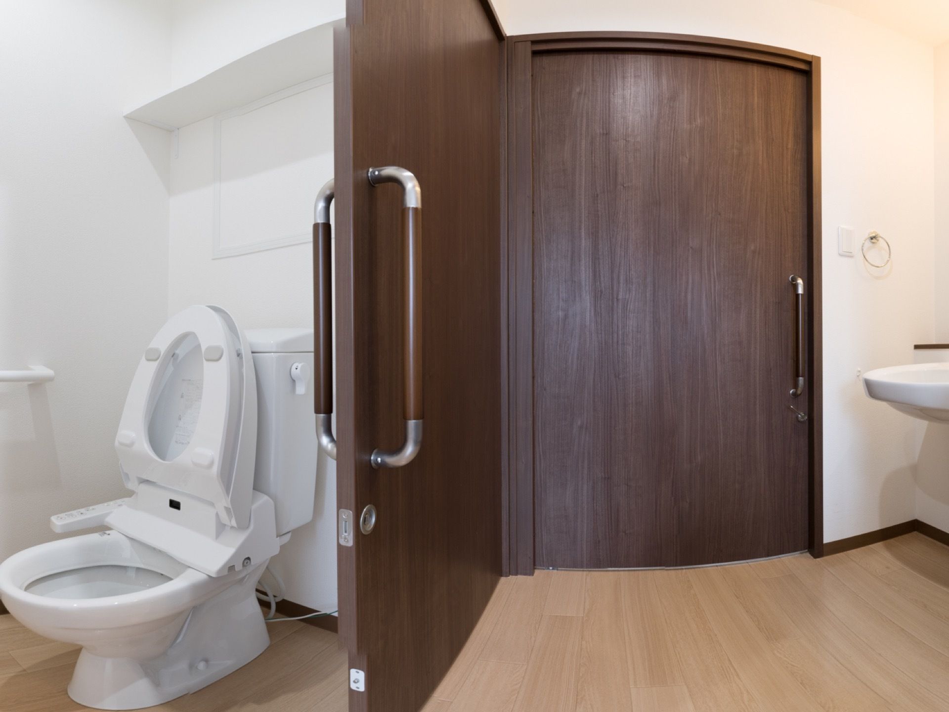 部屋の入口を入るとすぐにトイレがある。部屋のドアもトイレのドアも同じこげ茶色で、手すりがついており、横にスライドして開け閉めできる。