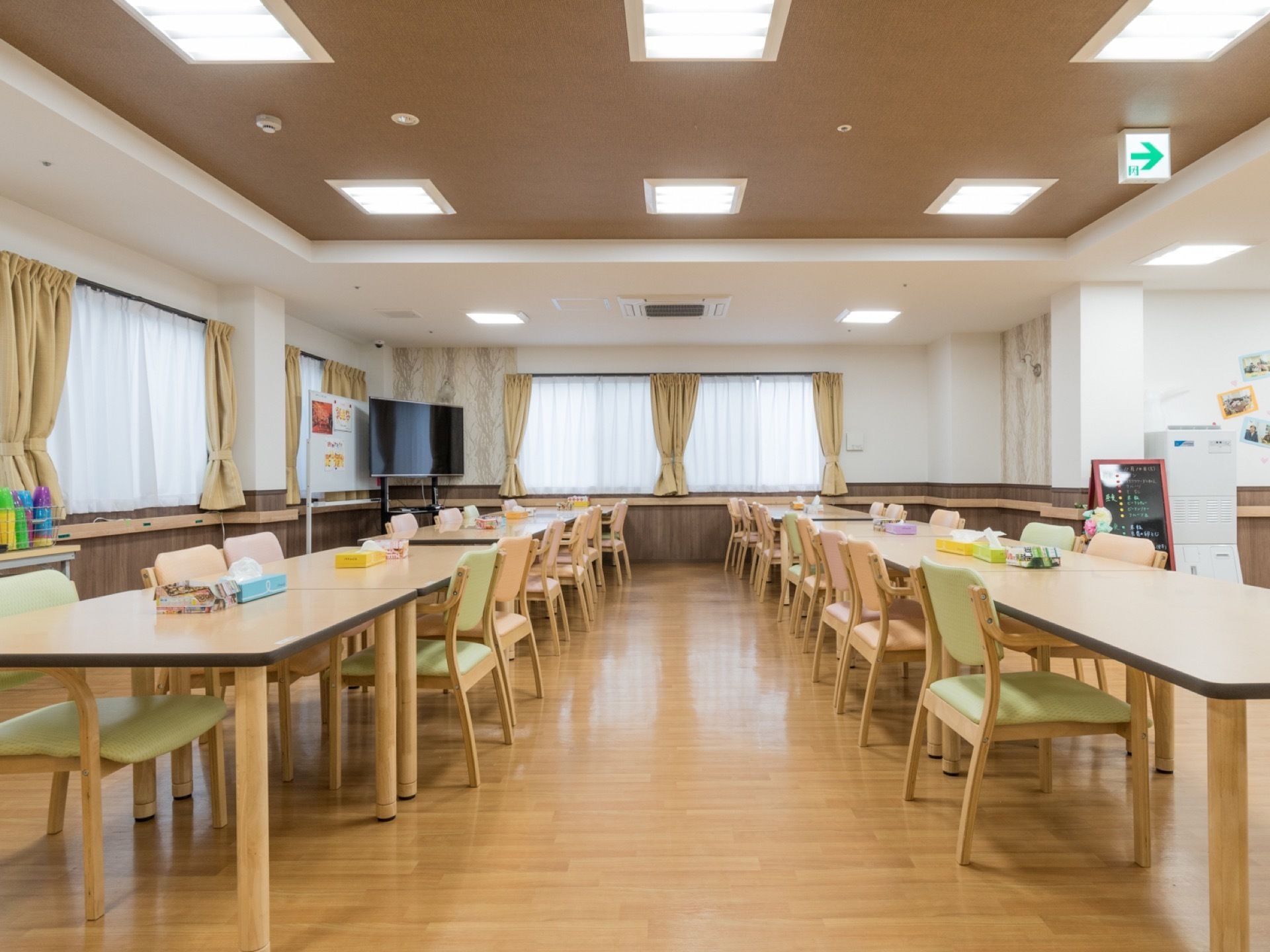 食堂にはテーブルをつなげて長く２列に並べている。テーブルの角が丸くなっており、椅子の背もたれはパステル調の色合いである。