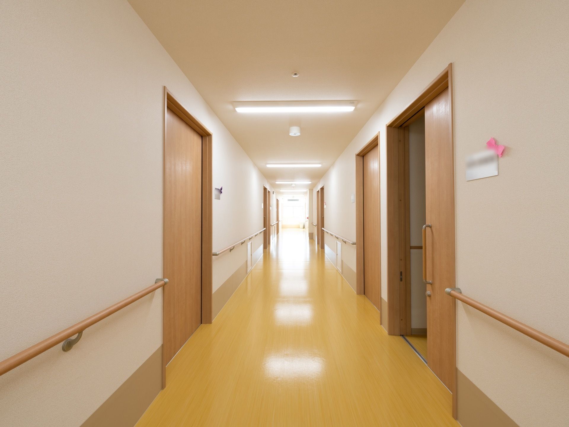 通路の床はフローリングになっており、両側には部屋の扉が複数、並んでいる。長い手すりが取りつけられている。