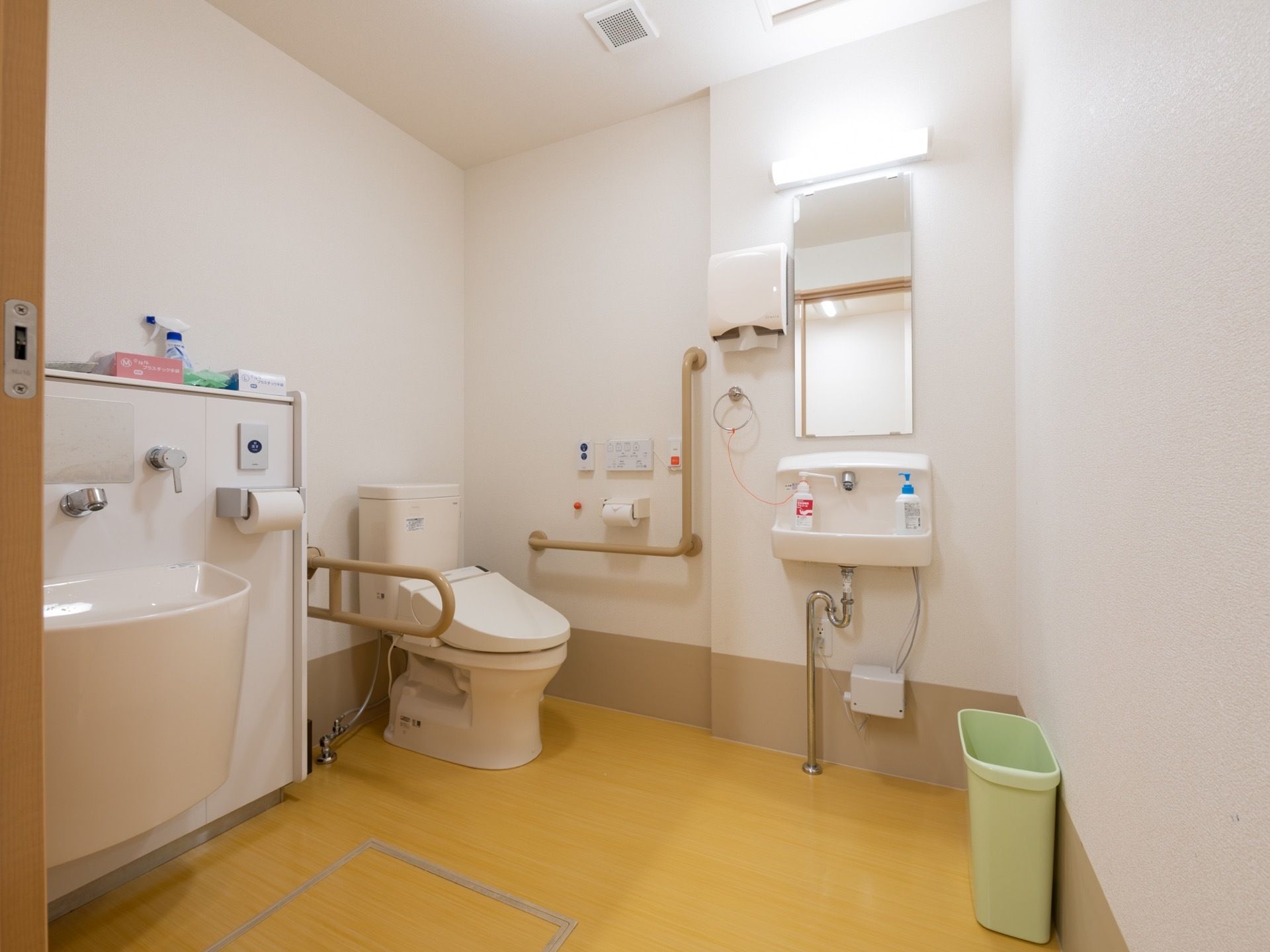 広々としたトイレスペースがある。洋式便器が設置されている両側にはそれぞれ手すりが設けられている。呼び出しボタンもある。