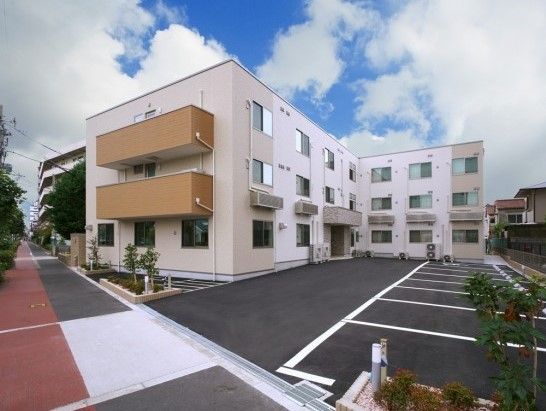 三階建てのマンションのような外観の建物である。広々とした駐車場から玄関までは段差もなく、快適にご移動いただける。