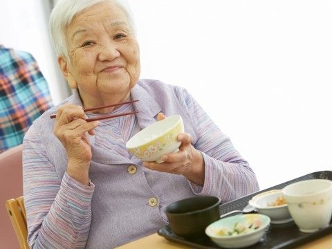 ダイニングルームでの食事中に笑顔で写真に納まる入居者様