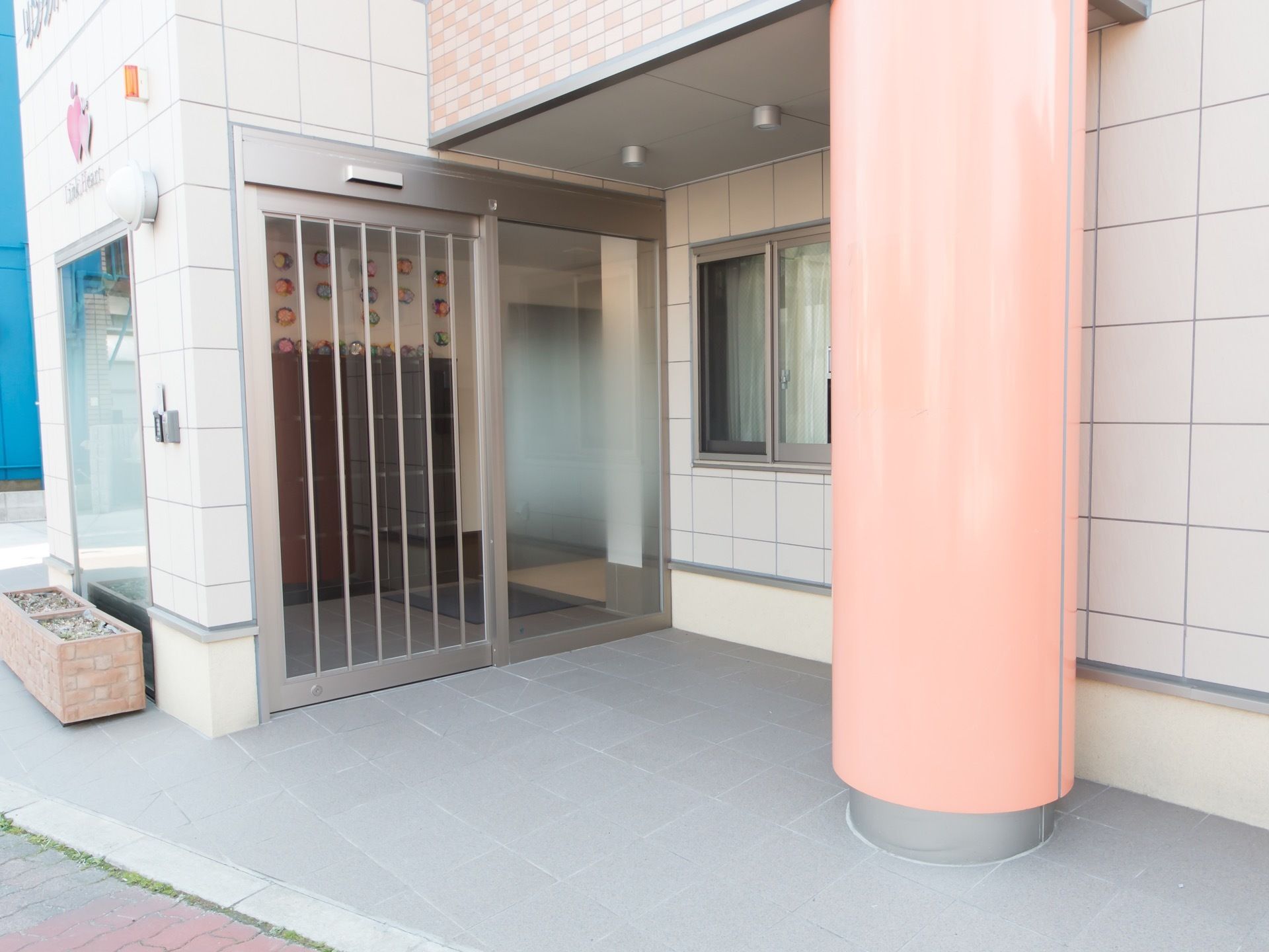 緩い傾斜がついたエントランスである。インターホンのほか、受付用の窓が設置されている。玄関扉には、自動ドアが採用されている。