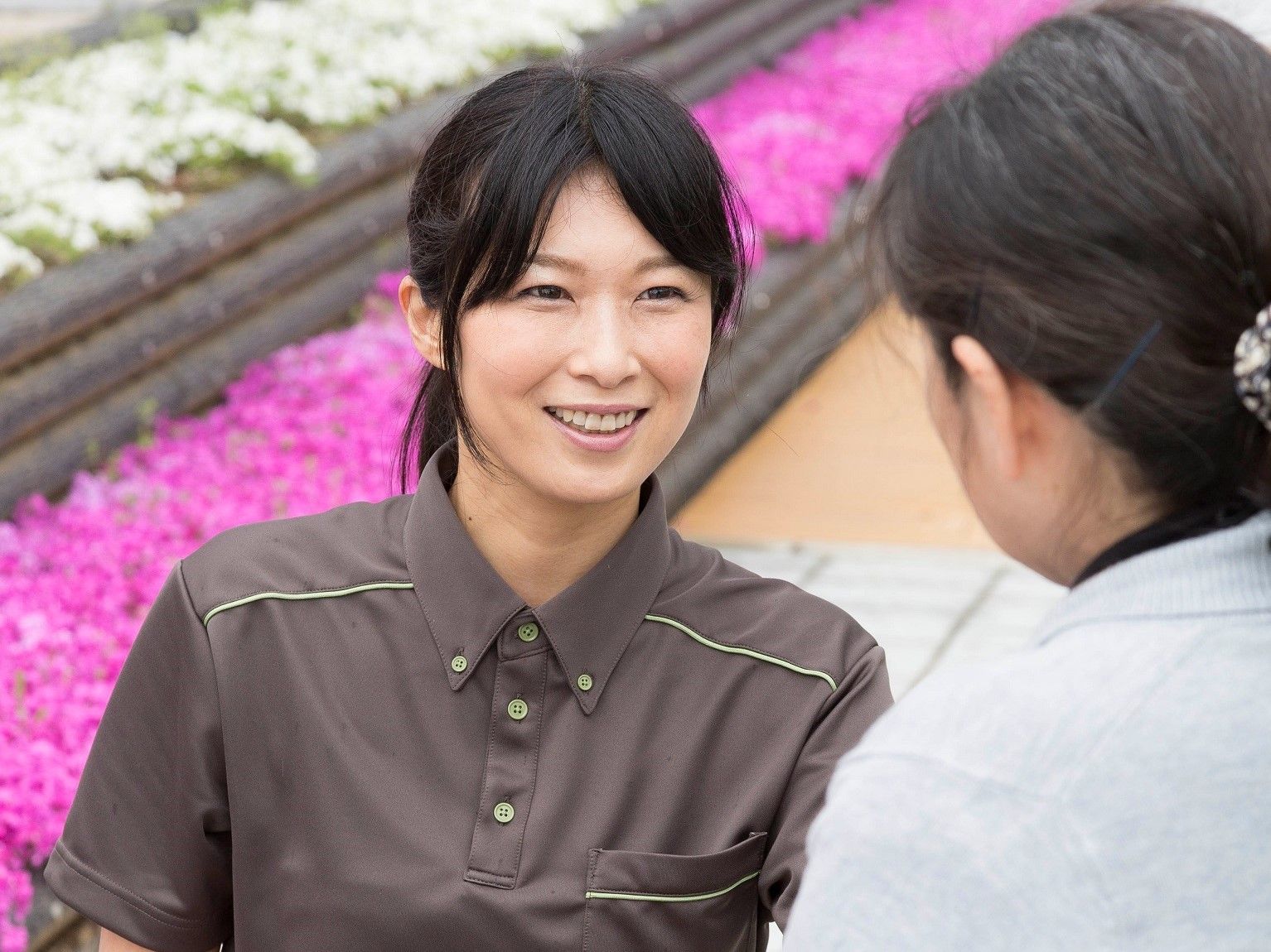 施設内の花壇そばで、笑顔で入居者様と接する施設スタッフ