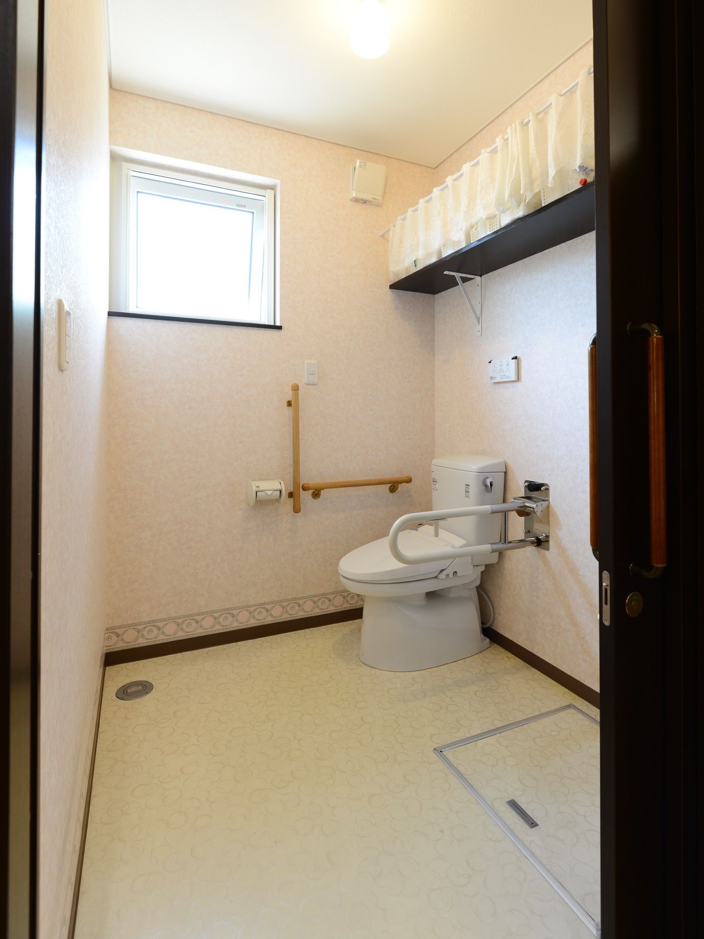 スペースが広く確保されたトイレである。壁には手すりが備わっており、窓からは光が差し込み明るい。扉はスライド式になっている。