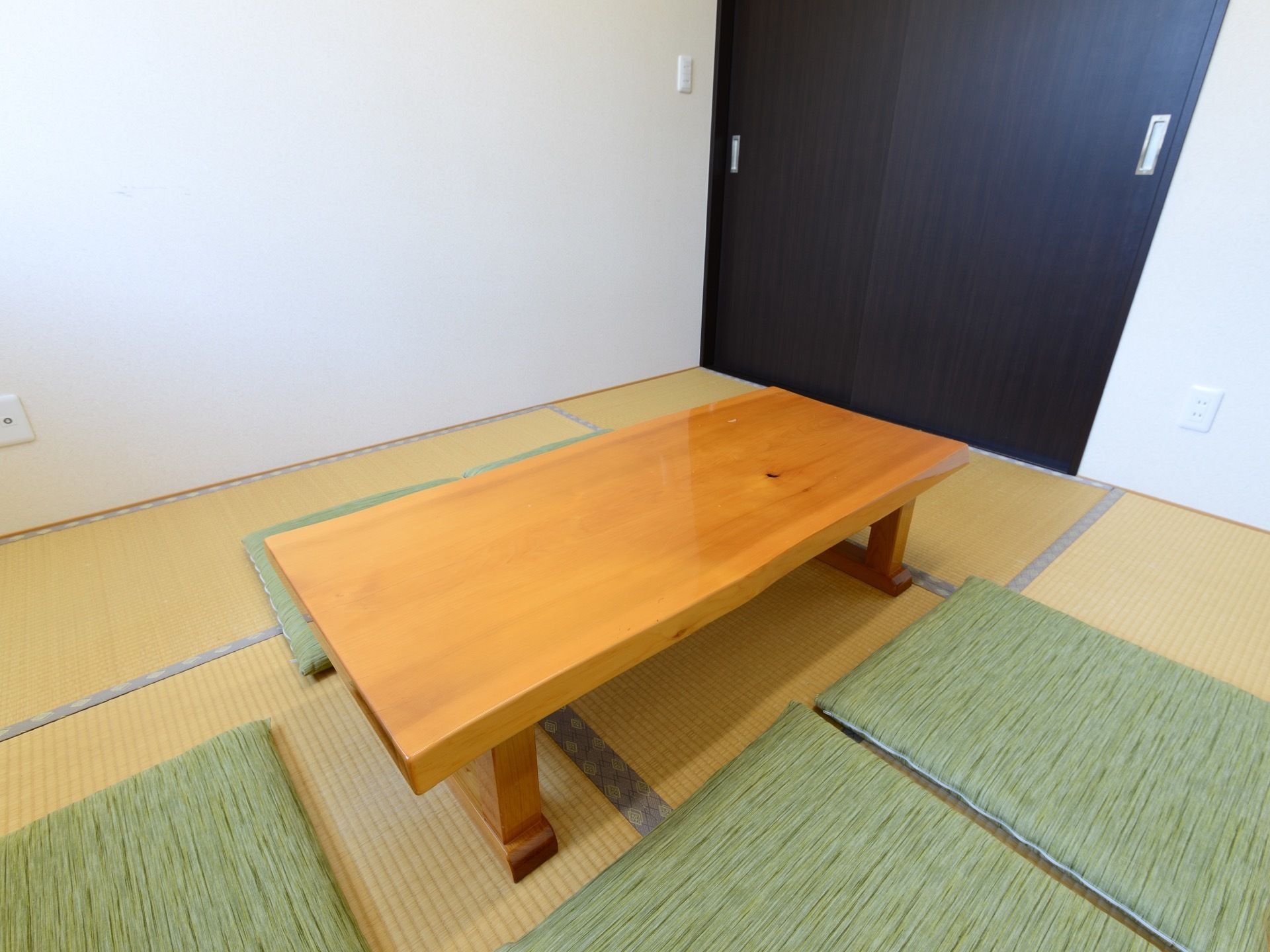 畳の部屋にテーブルと座布団が置かれている。入り口はシックなダークブラン調のスライド式になっており、開口部が広く開く。