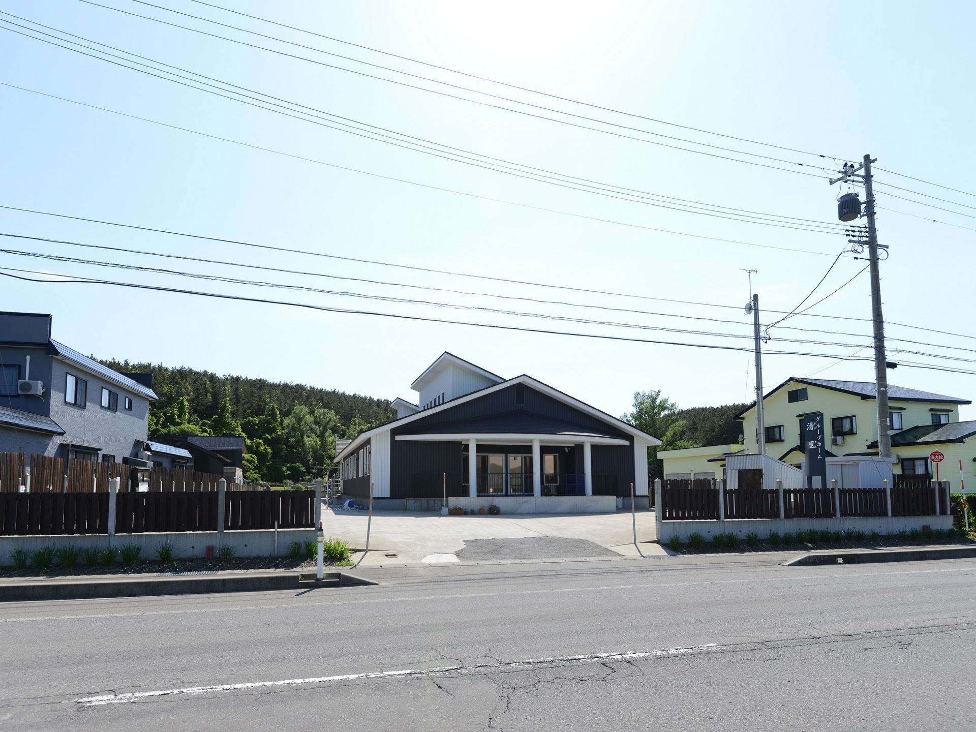 ホワイトとブラック調のモダンな施設外観である。道路に面しており、敷地内には施設名が記された看板が設置されており、道路から目立ちやすい。