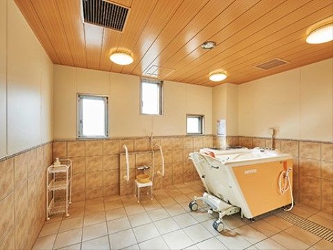 オレンジ系の色彩を取り入れた浴室は温かい印象である。壁に上下の配置で窓を設けている。天井に円形の照明を数ヶ所に設置している。