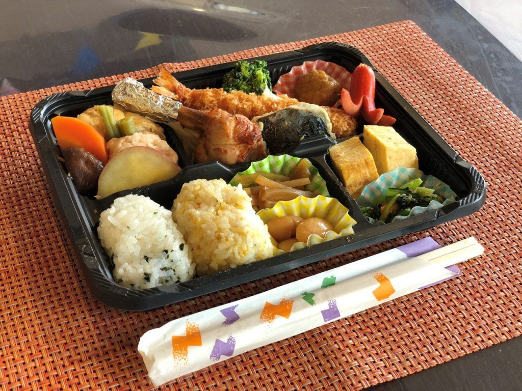 おにぎりと赤ウインナー、海老フライやチキン、野菜の煮物が入った弁当
