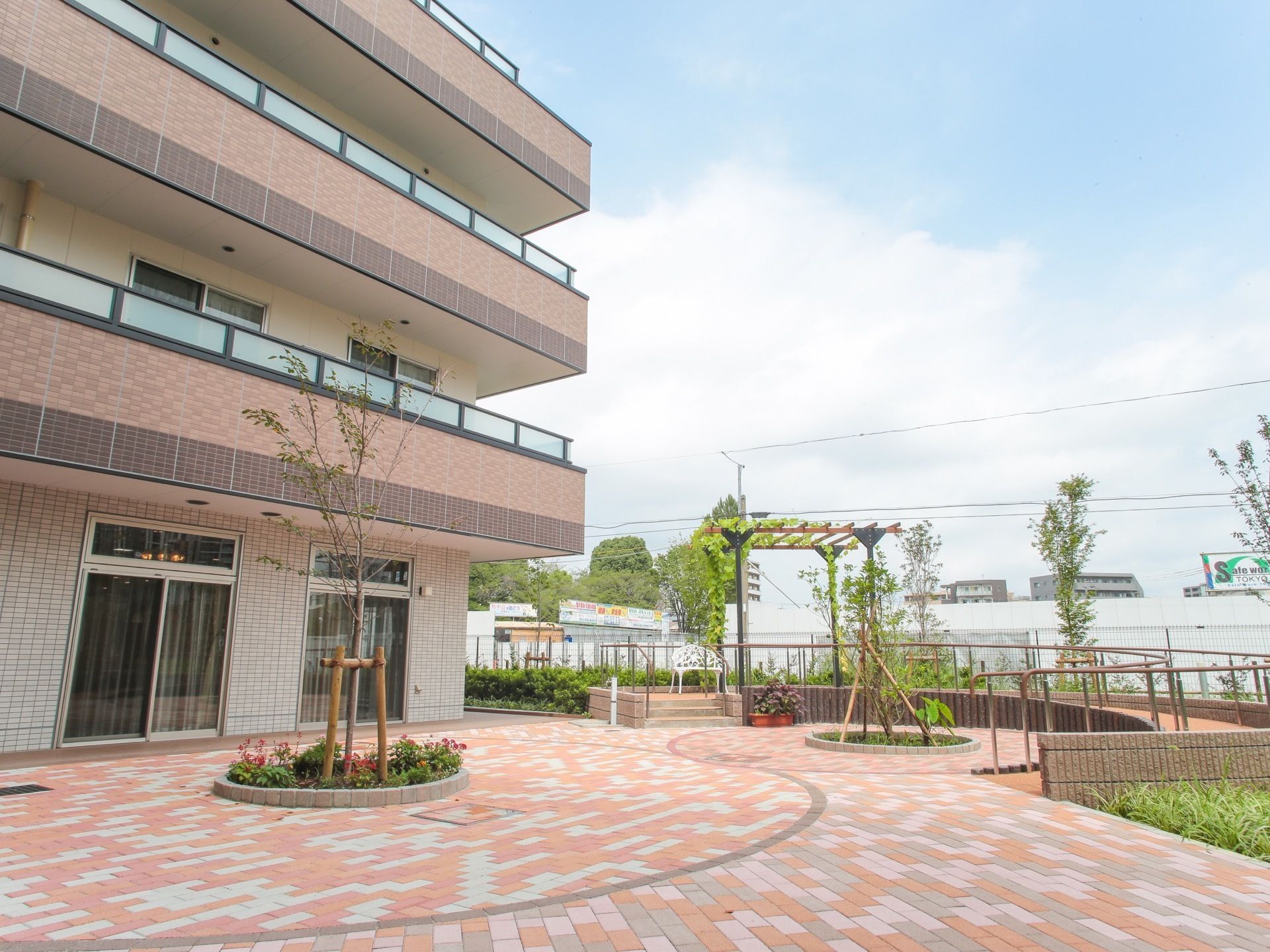 介護施設の外観と、草花やベンチがあるレンガ畳の中庭
