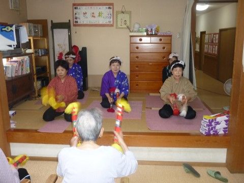 伝統芸能を披露する演者と、向いあって一緒に体験する入居者様