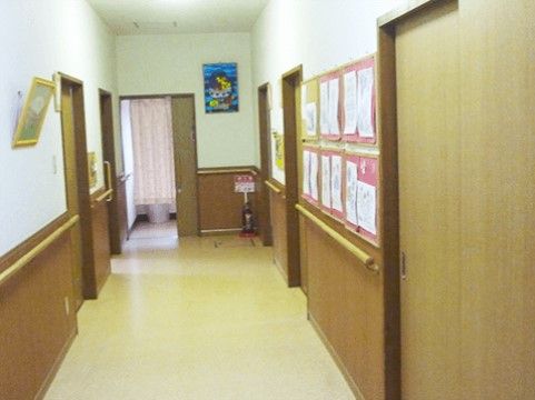 廊下の壁には手すりが設置されており、足腰が不安な方でも捕まりながら歩行することができる。壁には掲示物が貼られている。