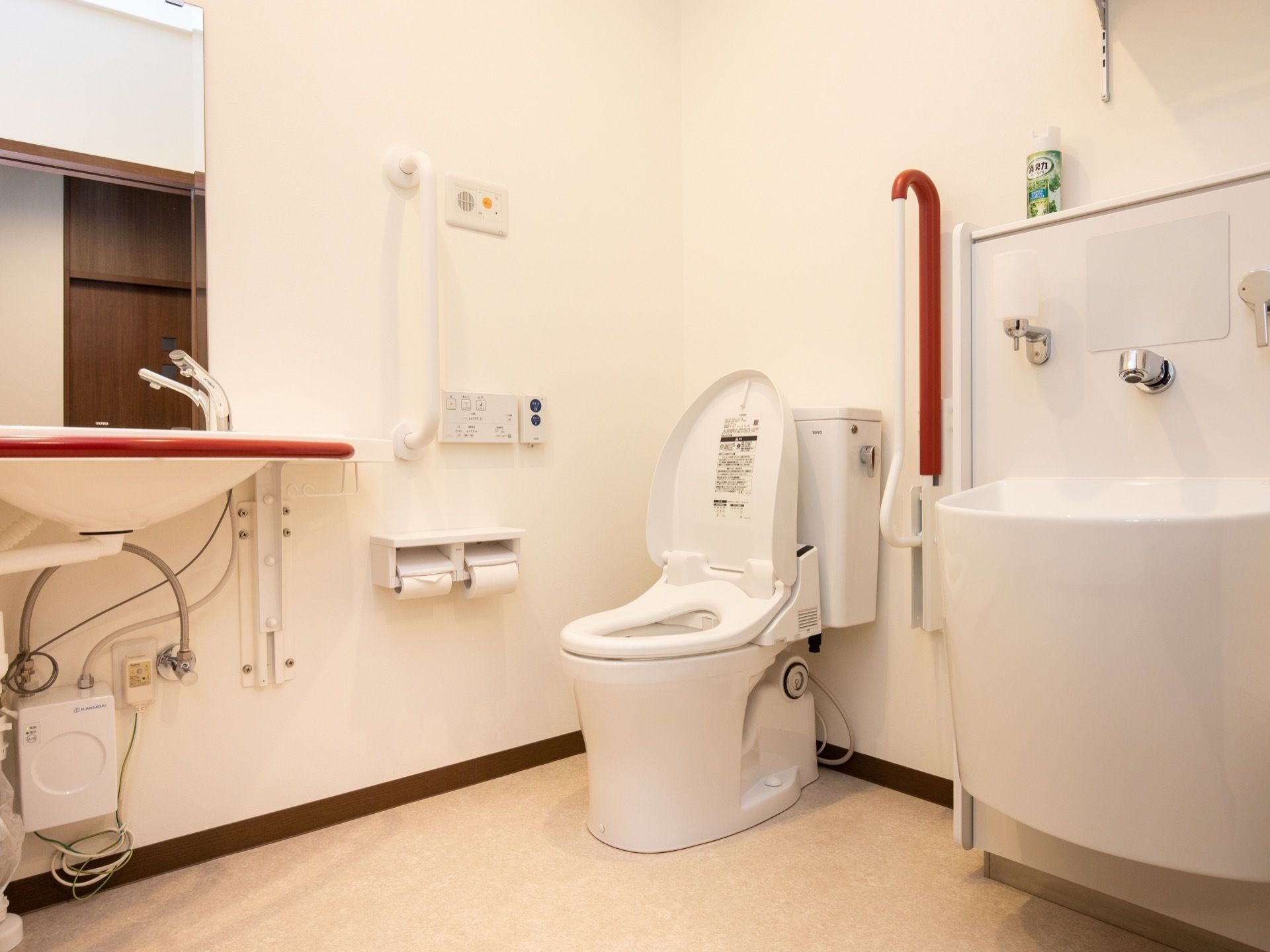 トイレの内装は白を基調としている。可動式の手すりと洗面ボウルの側面はえんじ色に配色されており、目立っている。